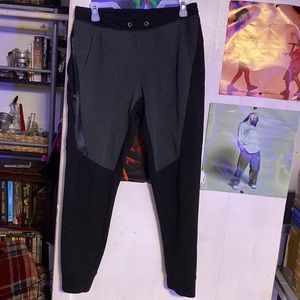 Black and grey sweatpants with one zipper pocket and one regular pocket.